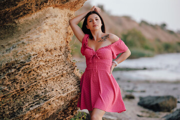 Beautiful woman in pink dress posing near cliff