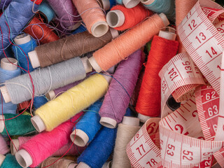 Lots of colorful sewing threads on spools with measuring tape on the right