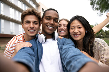 Happy carefree group of friends taking a selfie laughing.Multiracial young relaxed people having...