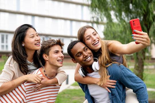Happy carefree group of friends taking a selfie laughing.Multiracial young relaxed people having fun and taking pictures outside.