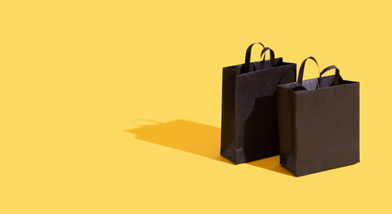 Black paper shopping bags on yellow background. Black friday sale, shopping concept. Banner with...