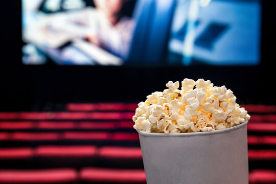Movies and popcorn. Pop corn at cinema. Family film night concept. Action or romantic comedy entertainment on screen. Dark theater with red seats. Salty snack in bucket or box. Spectator or critic pov