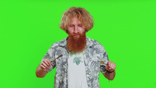 Ready to eat. Hungry young man waiting for serving dinner dishes with with restlessness holding cutlery fork knife, will appreciate delicious restaurant meal. Guy isolated on chroma key background