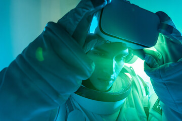 Male astronaut in spacesuit touching virtual reality goggles over head