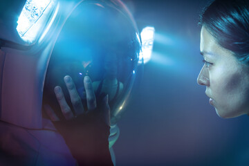 Astronaut couple with woman in casual clothes dressing man standing in helmet and spacesuit