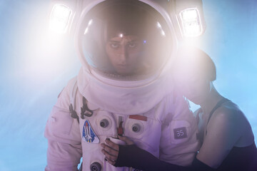 Astronaut couple with woman in casual clothes standing and hugging man in spacesuit