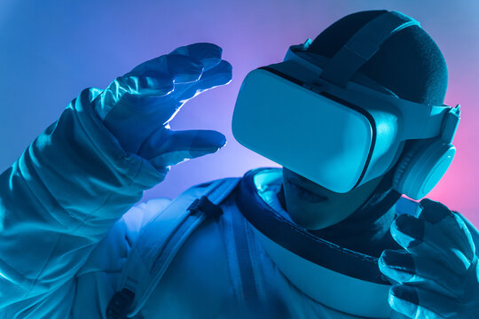 Anonymous astronaut in spacesuit wearing VR goggles with headphones