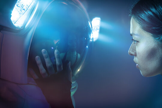 Astronaut couple with woman in casual clothes dressing man standing in helmet and spacesuit