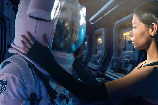 Astronaut couple with woman in casual clothes dressing man standing in helmet and spacesuit