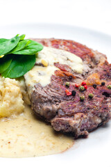 beef steak with sauce, mashed potatoes and spinach leaves