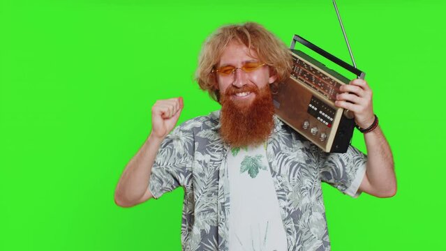 Happy young caucasian man using retro tape record player to listen music, disco dancing favorite track, having fun, entertaining, fan of vintage technologies. Guy isolated on chroma key background