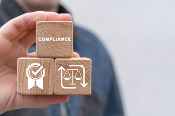 Man holding wooden cubes sees word: COMPLIANCE. Corporate regulatory and compliance business...