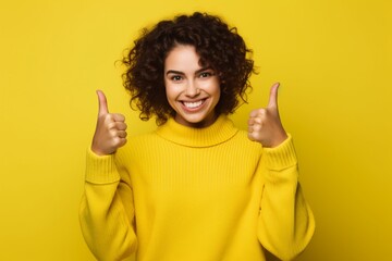 young women happily keeping thumbs up on isolated yellow background copy space
