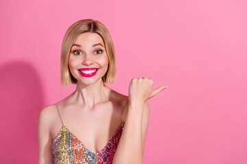 Portrait of toothy beaming girl with blond hair wear sequins dress impressed directing empty space isolated on pink color background