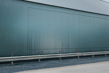 Fototapeta na wymiar Industrial warehouse with empty grey steel wall standing on roadside of highway side view