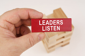 In the hands of a man there is a red wooden plate with the inscription - Leaders Listen