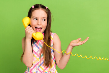 Photo of charming adorable girl wear stylish sarafan speak phone discuss gossip secrets look empty space isolated on green color background