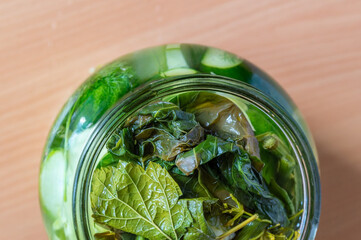 Top view of jar with pickled vegetables covered with leaves