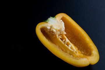 Slice of yellow bell pepper on a black background. Close up.