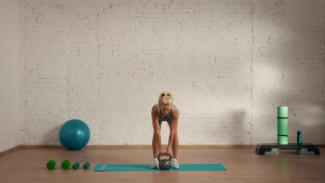 Healthcare and wellness advertisement concept. Athletic woman fitness coach doing kettlebell back bends for online classes.