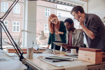 Diverse trip of young architects using a tablet together in a office