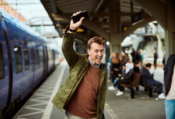 Middle aged man using his smartphone while waiting in the train station