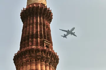Fotobehang Qutb Minar minaret with airplane in sky background, tower part Qutb complex in South Delhi, India, big red sandstone minaret tower landmark popular touristic spot in New Delhi, tallest brick minaret © TRAVELARIUM
