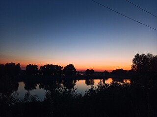 crimson sunset on the river, silhouette of trees
