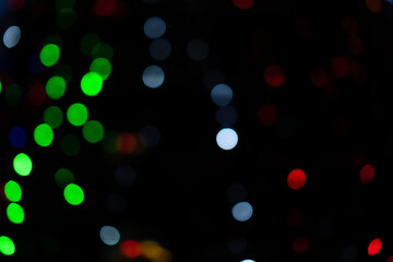 Bokeh, colorful bright green, red, blue lights blurred on the street. Unfocused sparkling lights on the street