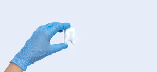 Doctor hands holding big tooth on blue background. Healthy care teeth concept. Top view, flat lay. Copy space for your text.