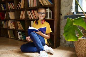 Portrait of happy schoolboy child doing creative homework at library