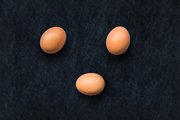 Closeup of brown organic free-range chicken eggs isolated on a slate background from above, top view