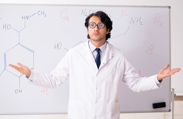 Young funny chemist in front of white board