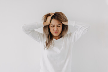 Asian Thai woman standing facial expression and grabbing hair, got headache with migraine, thinking too much, have no idea, tired in white apartment room in winter. - obrazy, fototapety, plakaty