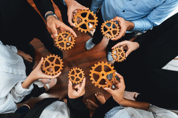 Group of multiracial business people joining gear wheels together as effective unity and productive teamwork concept. Efficient system business team process for solution solving. Meticulous