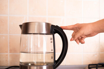 Kettle. Electric kettle. Hot water. Electricity. Warm. Tea. Hot tea. Button. Turn on the kettle. The hand presses the button. Heat water
