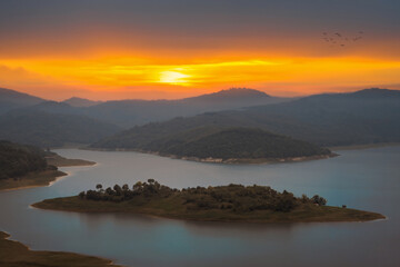 Sunset in the mountains with small land in the lake.