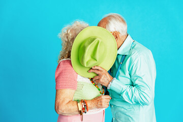 Beautiful senior old couple wearing fancy party clothes acting in studio on a colored background....