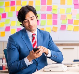 Young handsome employee with many conflicting priorities