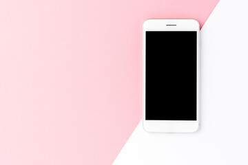 Overhead shot of white mobile phone with blank screen on abstract background with copyspace. Flat...