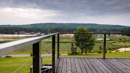 View from wooden deck over the little city Krasnobród, Rozotcze, Poland. Lake, beach and hills covered with forest in the background. Cloudy, summer day.