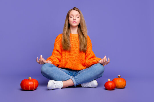 Full length photo of chill young girl closed eyes sitting in lotus position meditation halloween spirit isolated on purple color background