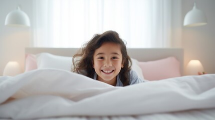 Little girl laughing and having fun in bed