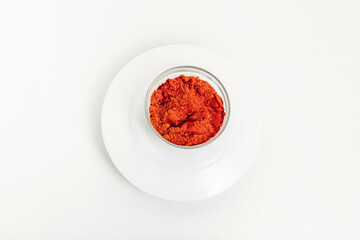 Red paprika in a glass plate on a white background.