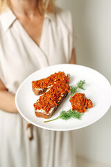 A female nutritionist holds sandwiches with adjika in her hands.