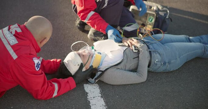 Emergency, paramedic and people on road for accident, injury and car crash for saving patient. Healthcare, ambulance and health emt with person for medical service, care and first aid in street