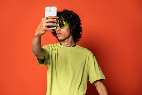 Happy young ethnic man taking selfie with smartphone