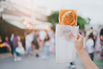Woman hand hold Taiyaki on street.