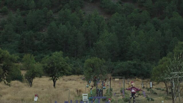 A resting place by the roadside at the foot of the Mountain. A scarecrow and a sign saying "Lavanta" with swings behind it.