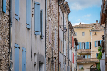 Fototapeta na wymiar Narrow street and old house stone facades with shutters in the medieval village of Chatillon en Diois, in the south of France (Drome)